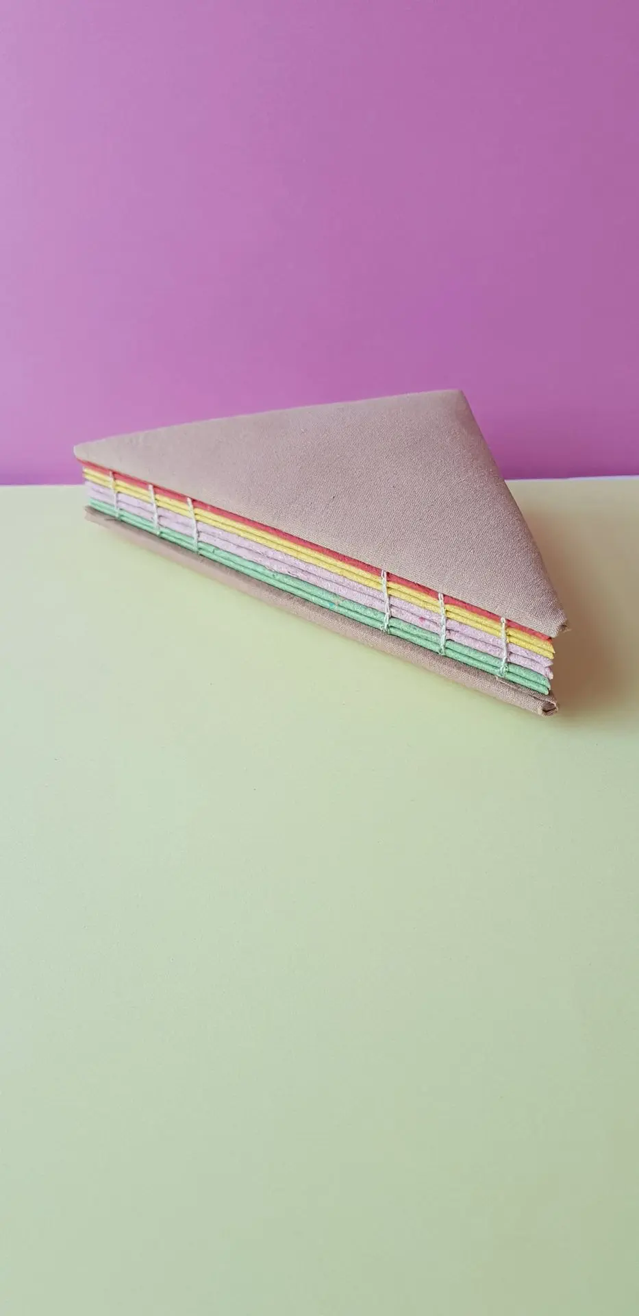 Carnet club sandwich triangulaire avec une reliure visible et des feuilles au couleurs de tomate, fromage, jambon et salade. 